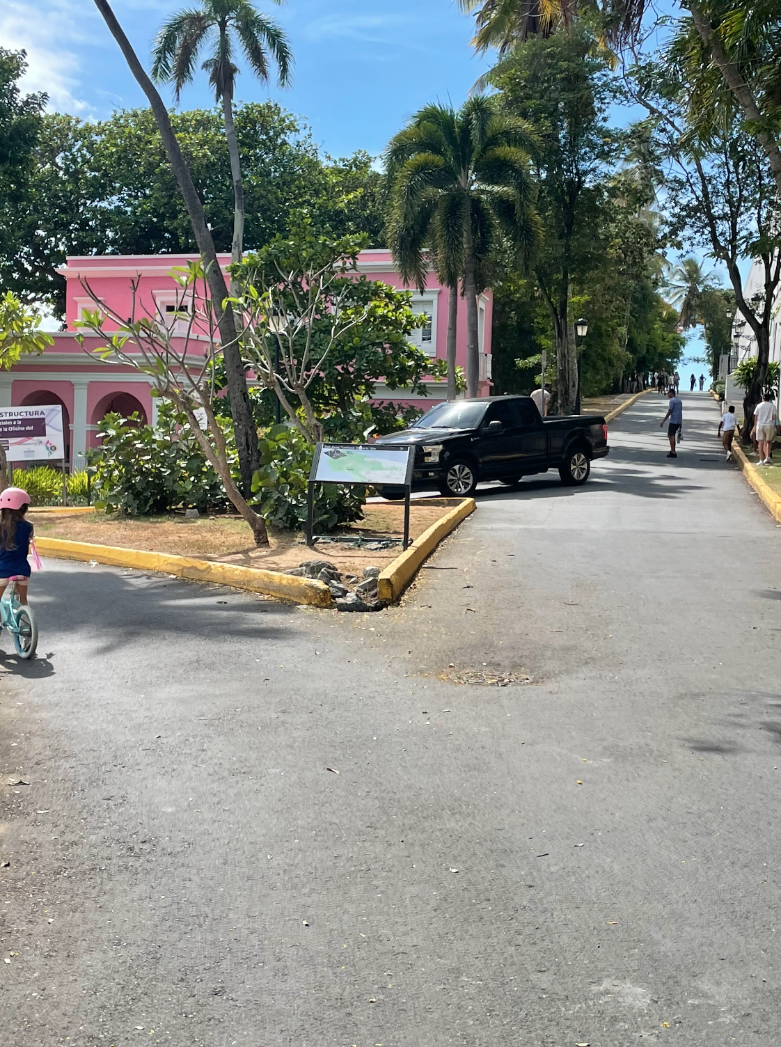 La intersección de Las Monjas hoy — niña en bici, isleta funcional, sin rotonda
